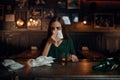 Drunk woman wipes her nose with a napkin in bar