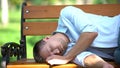 Drunk young man sleeping on bench in park, youth lifestyle, harmful addiction