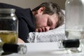 A drunken alcoholic man lies on the bed, empty bottles on the table. Alcoholism, alcohol dependence as a social problem