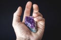 Druse of natural untreated violet crystals of amethyst on a piece of rock lies on the palm of your hand
