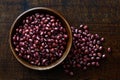 Dry adzuki beans in dark wooden bowl isolated on dark brown wood