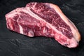 Dry-aged Raw T-bone or porterhouse beef marbled meat prime steak, on black stone background