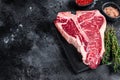 Dry-aged Raw T-bone or porterhouse beef meat Steak with herbs and salt. Black background. Top view. Copy space Royalty Free Stock Photo