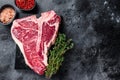 Dry-aged Raw T-bone or porterhouse beef meat Steak with herbs and salt. Black background. Top view. Copy space Royalty Free Stock Photo