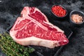 Dry-aged Raw T-bone or porterhouse beef meat Steak with herbs and salt. Black background. Top view