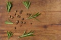 Dry allspice peas and rosemary branches on a wooden background