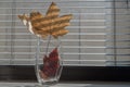 Dry autumn maple leaves standing in transparent glass vase. They are on windowsill on background of dusty window with brown blinds Royalty Free Stock Photo