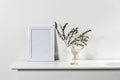 Dry branch of eucalyptus in a white figured earthenware vase. A figurine of a pink bird and a cup on the table. Scandinavian style