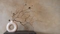 Dry branch of in round modern white vase against beige wall