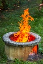 Dry branches burn in campfire pit in the garden. High bright flames flickering on open garden fire pit