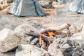 Dry branches and firewood are burning in bonfire near tent in mountain.