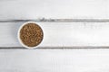 Dry buckwheat in white ceramic bowl isolated on grey table. Spilled buckwheat. Royalty Free Stock Photo