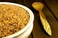 Dry bulgur wheat in a clay bowl with spoon on the table