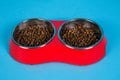 Dry cat food in bowls isolated on blue Royalty Free Stock Photo