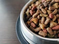 Dry cat food in a stainless steel bowl on wood table. Royalty Free Stock Photo