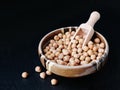 Dry chickpea beans in bowl with wooden scoop over black background