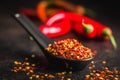 Dry chili pepper flakes. Crushed red peppers in spoon on black table Royalty Free Stock Photo