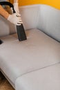 Dry cleaner's employee removing dirt from furniture in flat, closeup. Cleaning sofa with professional chemicals