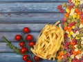 Dry colorful Italian pasta fettuccini and farfalle or bows with tomatoes and rosemary Royalty Free Stock Photo