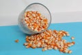 Dry corn in glass on blue background, top view