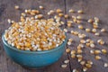 Dry corn kernels in a green bowl, set on wooden table Royalty Free Stock Photo