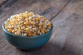 Dry corn kernels in a green bowl, set on wooden table Royalty Free Stock Photo