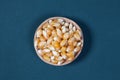 The dry corn kernels in a wooden bowl are placed on a green board with space Royalty Free Stock Photo