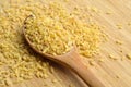 Cracked wheat daliya grains in wooden spoon, on bamboo cutting board Royalty Free Stock Photo