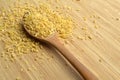Cracked wheat daliya grains in wooden spoon, on bamboo cutting board Royalty Free Stock Photo