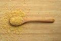 Cracked wheat daliya grains in wooden spoon, on bamboo cutting board Royalty Free Stock Photo