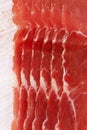 Dry cured ham slices on white wood background