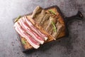 Dry-cured pork belly bacon with spices and rosemary close-up on a wooden board. horizontal top view