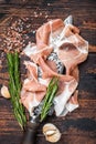 Dry cured Prosciutto crudo parma ham on a butcher knife. Dark wooden background. Top View