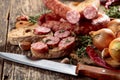 Dry-cured sausage with bread and spices on a old wooden table Royalty Free Stock Photo