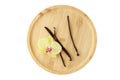 Dry dark brown vanilla pods and yellow orchid flower on bamboo wooden plate isolated on white background. Aromatic vanilla sticks Royalty Free Stock Photo