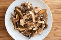 Dry dehydrated sliced mushrooms on a white dish wooden background close up shot