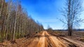 A dry dirt clay rural road in a field, stretching to the horizon in early spring. Rustic landscape