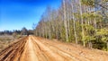 A dry dirt clay rural road in a field, stretching to the horizon in early spring. Rustic landscape