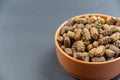 Dry dog food in a brown clay bowl against a gray background. The pellets are oval in shape. Food for neutered and spayed pets.