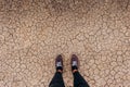 Dry land is covered with small cracks as a concept of drought and global warming. top view on legs in sneakers Royalty Free Stock Photo