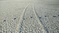 Dry earth cracks with foot prints and vehicle wheel trails