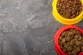 Dry food for cats and dogs in a yellow and red bowl on cement background