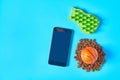 Dry food for pet near smartphone or tablet and rubber basketball ball and comb on blue background
