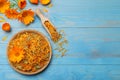 Dry and fresh calendula flowers on light blue wooden table, flat lay. Space for text Royalty Free Stock Photo