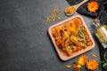 Dry and fresh calendula flowers with tincture on black table, flat lay. Space for text Royalty Free Stock Photo