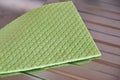 A dry, green, absorbent kitchen towel rests on a stainless steel sink. Close-up