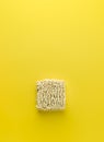 Dry instant noodles block on vibrant yellow background