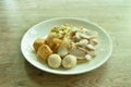 Dry large rice noodles dressing black sweet soybean sauce topping slice boiled pork and ball on plate Royalty Free Stock Photo