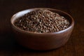 Dry linseeds in brown wooden bowl isolated on dark.