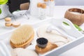 Dry lymphatic drainage massage wooden brushes, derma mezoroller and loofah pads for face and body skin care on a white tray.